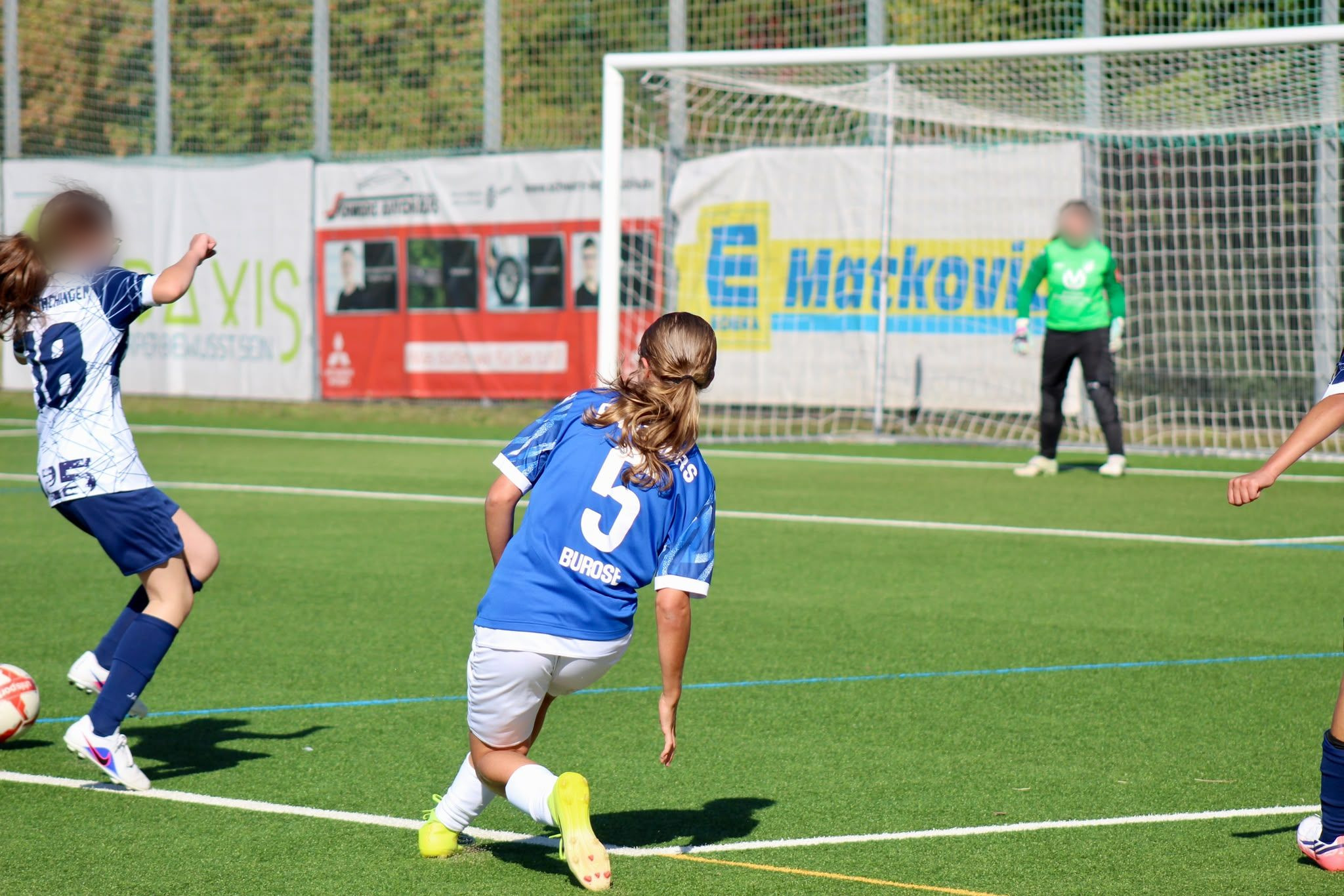 Spielerin des FC Panthers mit Rückennummer 5 und dem Namen Burose auf dem Trikot vor dem gegnerischen Tor, im Hintergrund die Torhüterin in Grün.
