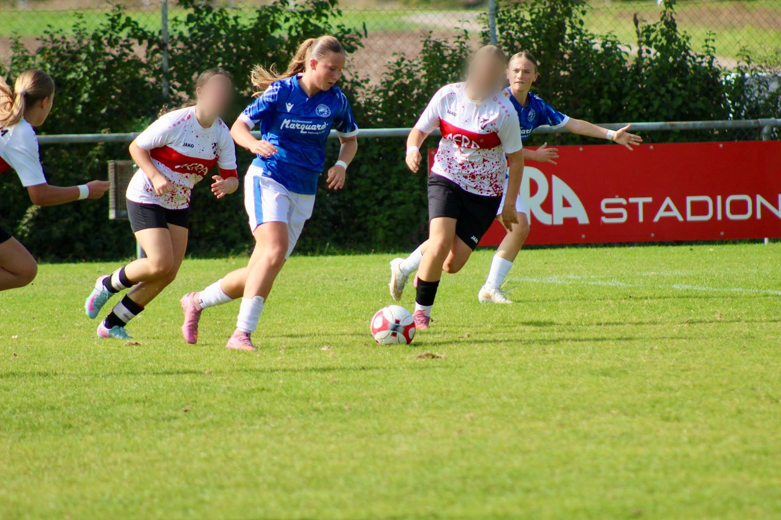 Spielerin des FC Panthers dribbelt zwischen zwei Gegenspielerinnen des SV Horrheim, im Hintergrund eine rote Werbebande